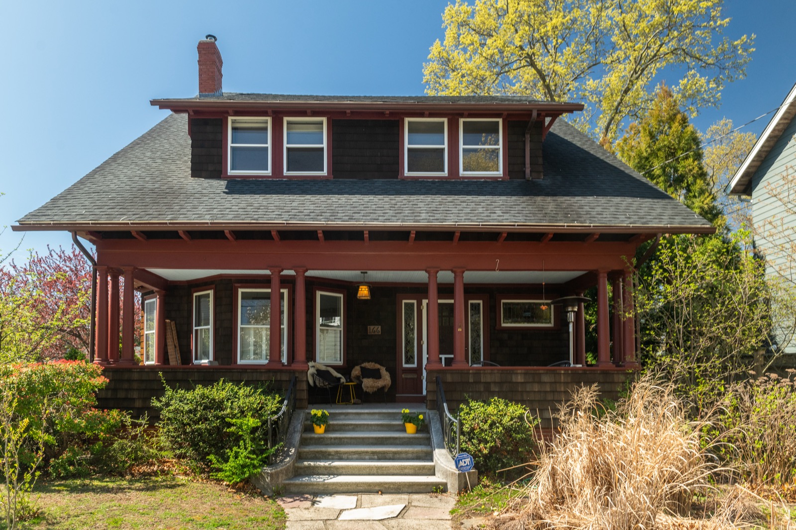 Front exterior of the Wheeler Lodge in spring with deep red trim and blooming tulips on the porch steps.