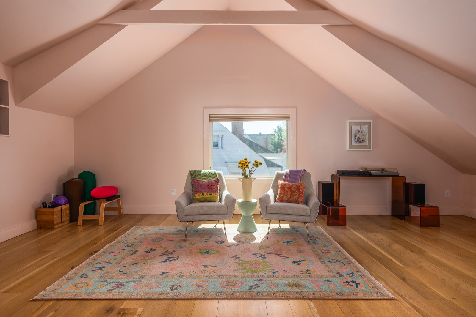 Sitting area in the primary suite with two armchairs beneath a tall gable window.
